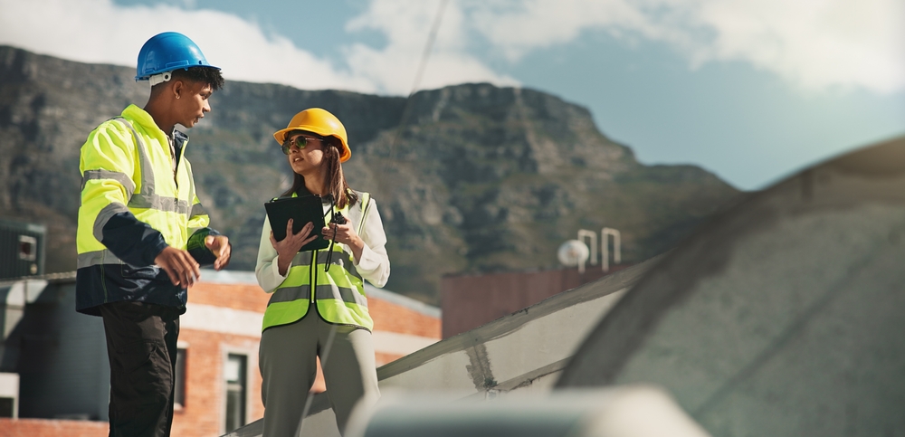 Woman, man and engineering with air conditioner on rooftop, discussion and tablet for inspection in city.
