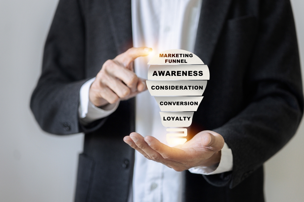 A man is holding a light bulb with the words marketing, funnel, awareness, consideration, conversion, loyalty written on it