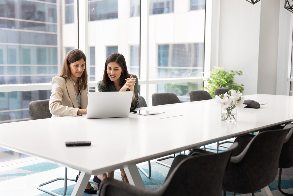 Two multiracial businesswomen engaged with laptop