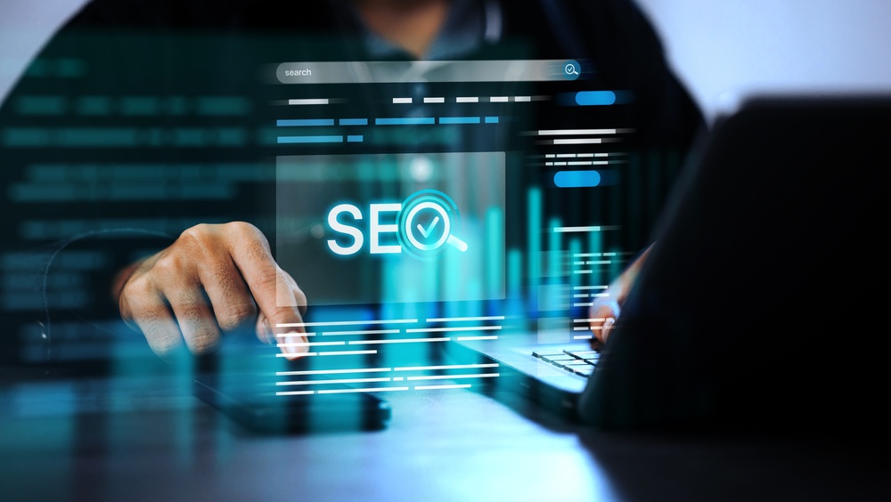 Digital marketer using laptop and phone with glowing SEO