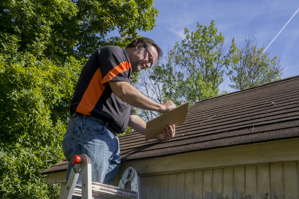 Contractor using a clipboard to figure our repair cost for hail damaged roof.