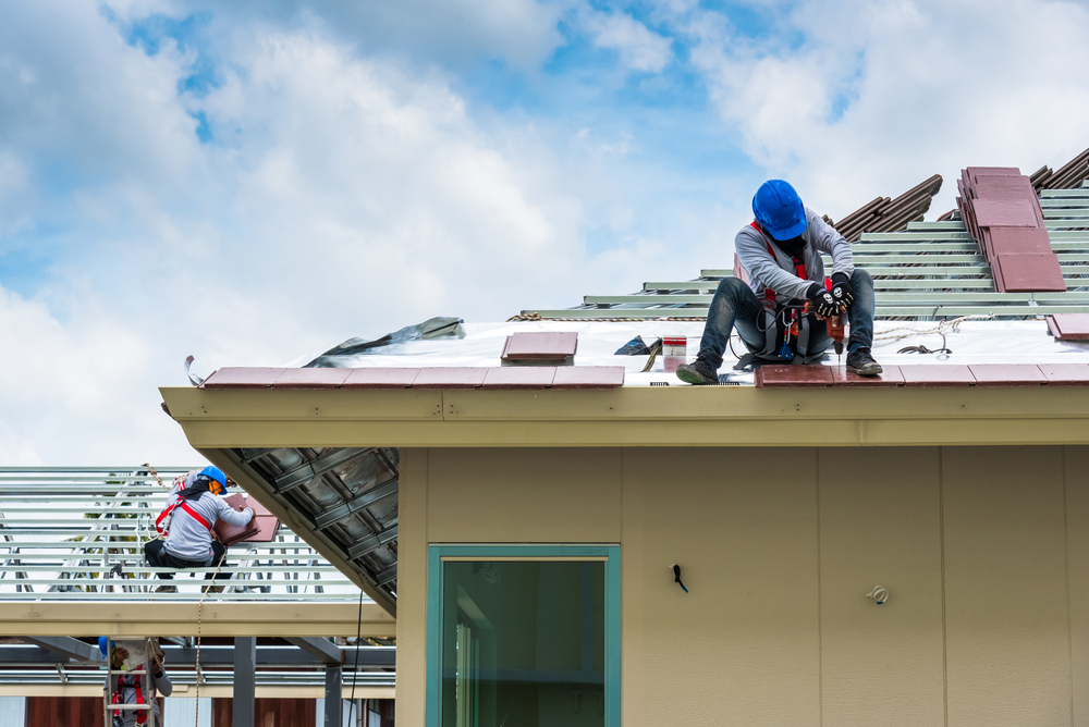 Workers are drilling roof tiles with a drill.